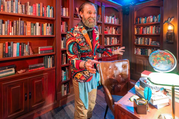 Man in brightly colored jacked stands before bookcases
